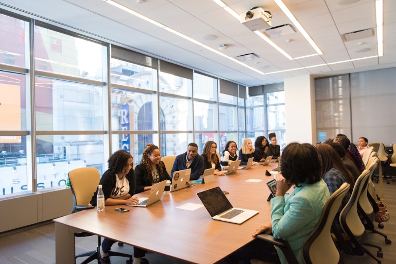 A group of people engaged in discussion at a conference table, focusing on knowledge management systems for business efficiency.